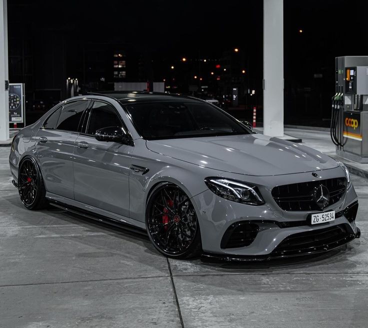 a mercedes benz amg is parked in front of a gas station at night with its lights on