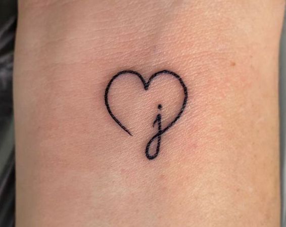 a small heart with an arrow tattoo on the side of the arm, and a music note in the middle