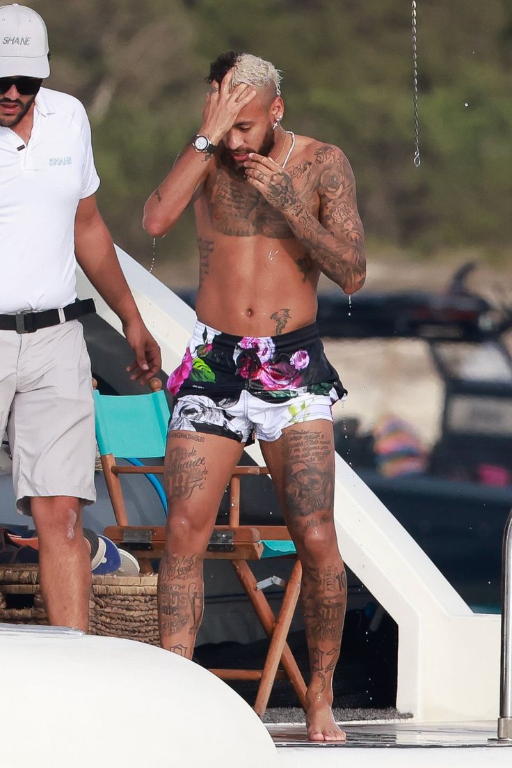 a man with tattoos standing next to another man on a boat