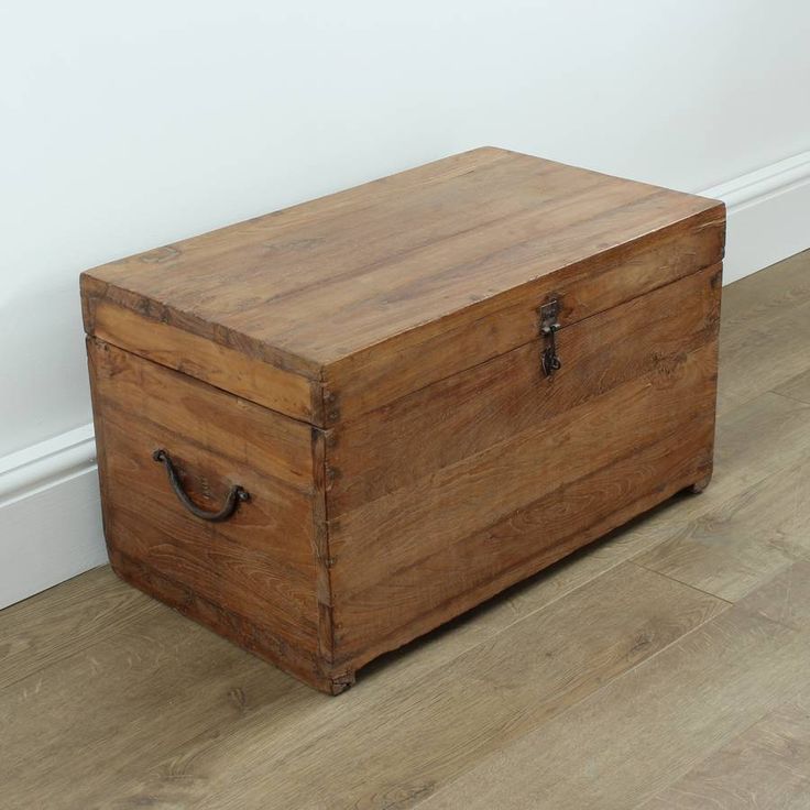 an old wooden box sitting on the floor in front of a white wall and wood floors