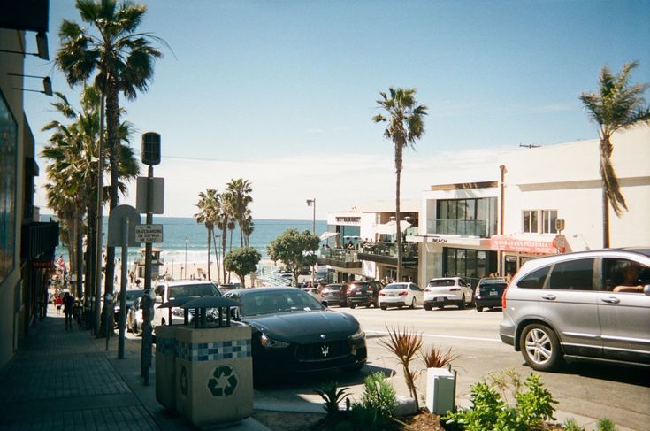 cars are parked on the side of the road near palm trees and beachfront buildings