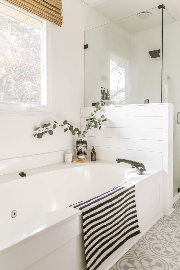 a white bath tub sitting under a bathroom window