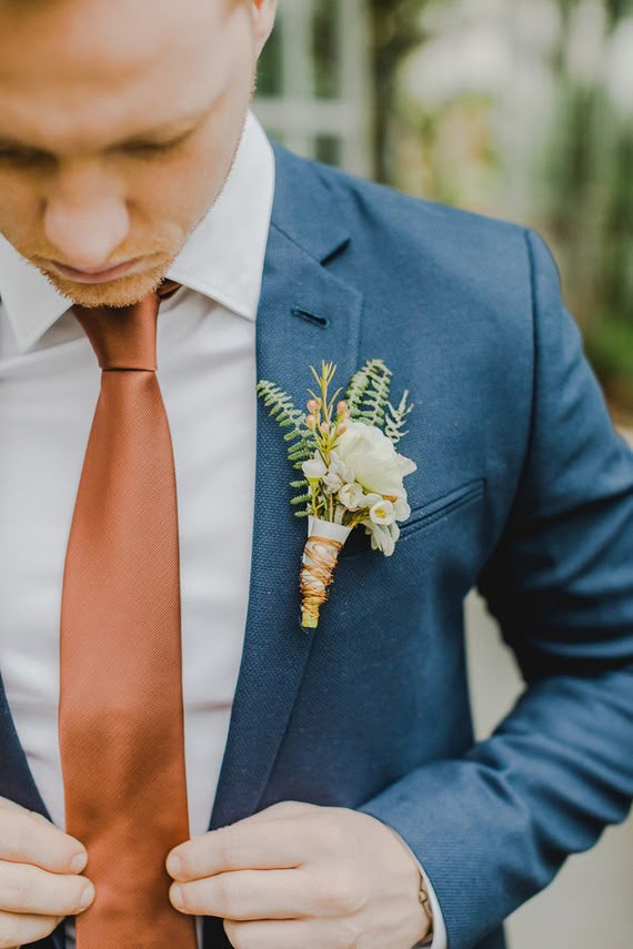 a man wearing a suit and tie with a boutonniere on his lapel