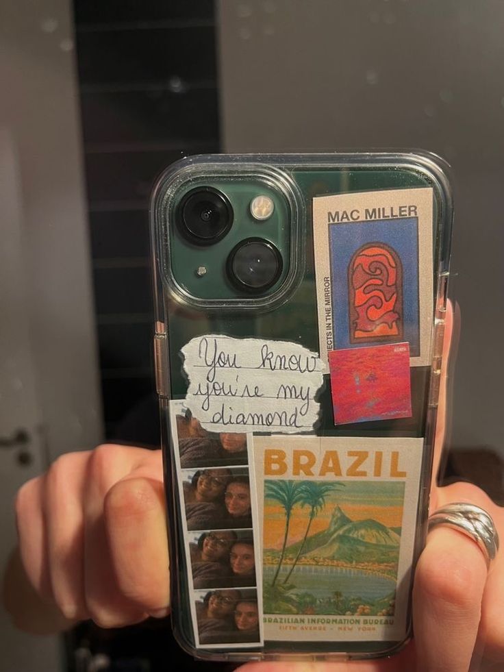 someone is holding up their cell phone case with some pictures and words on the back