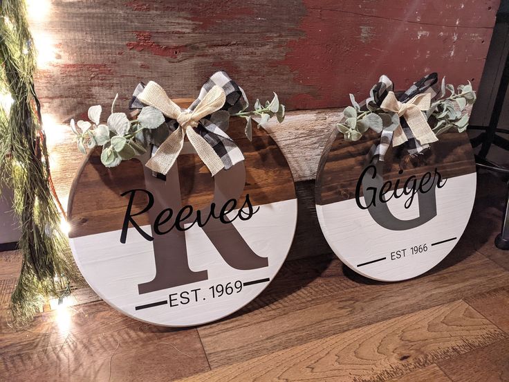 two round wooden signs with the letters k and r on them, decorated with greenery