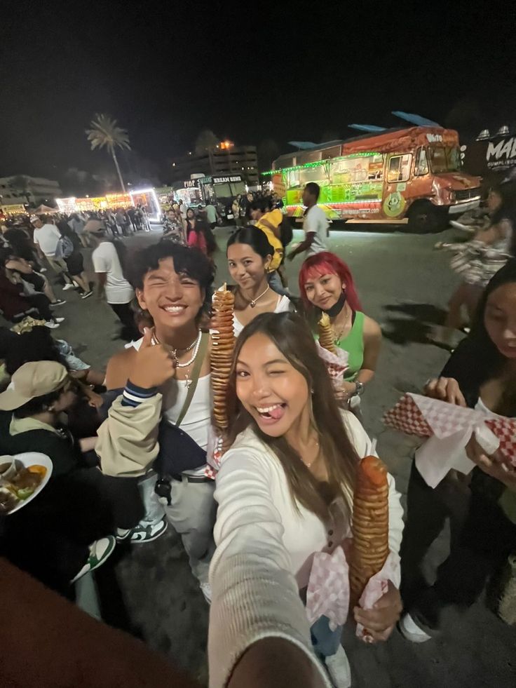 a group of people standing next to each other in front of food trucks at night