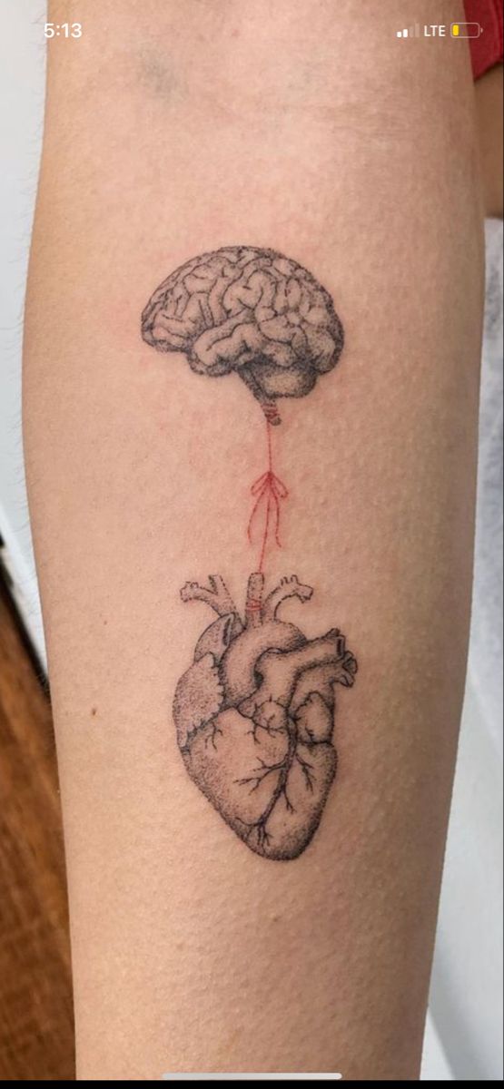 a heart and brain tattoo on the leg, with an arrow coming out of it