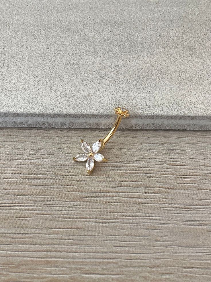 a gold flower brooch sitting on top of a wooden floor next to a wall