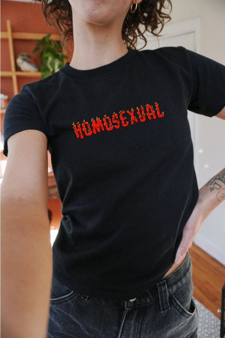 a woman wearing a black shirt with the word homosexuality spelled in red on it's chest