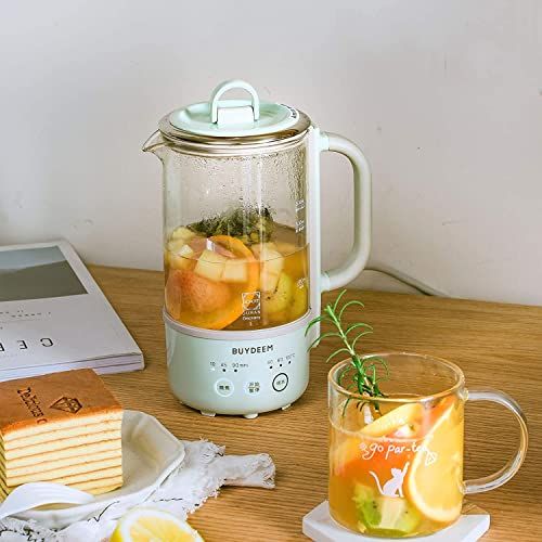 a blender filled with fruit sitting on top of a table next to slices of cake