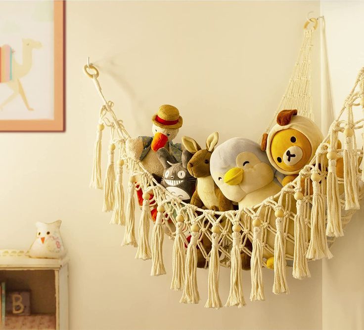 several stuffed animals in a hammock hanging on the wall