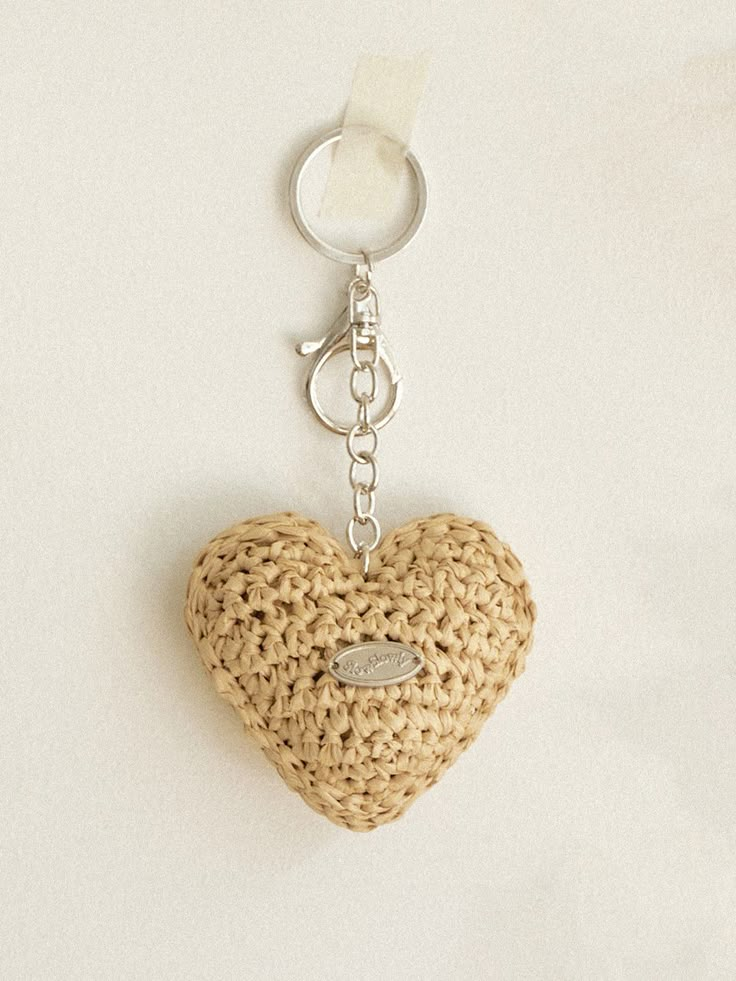 a crocheted heart shaped keychain hanging from a metal hook on a white surface