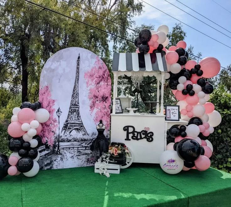 the dessert table is decorated with black and pink balloons, an eiffel tower backdrop