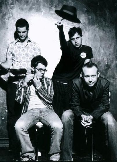 four men posing for a black and white photo with one holding his arm up in the air