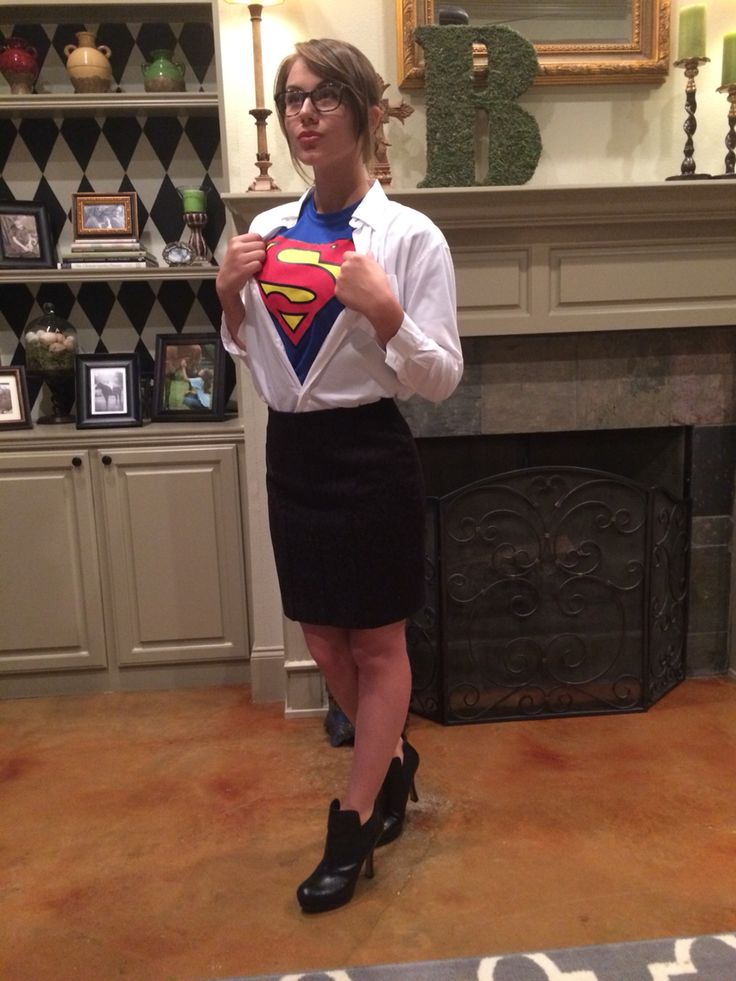 a woman standing in front of a fireplace holding a superman shirt