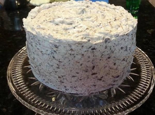 a cake with white frosting sitting on top of a glass plate next to a green bottle