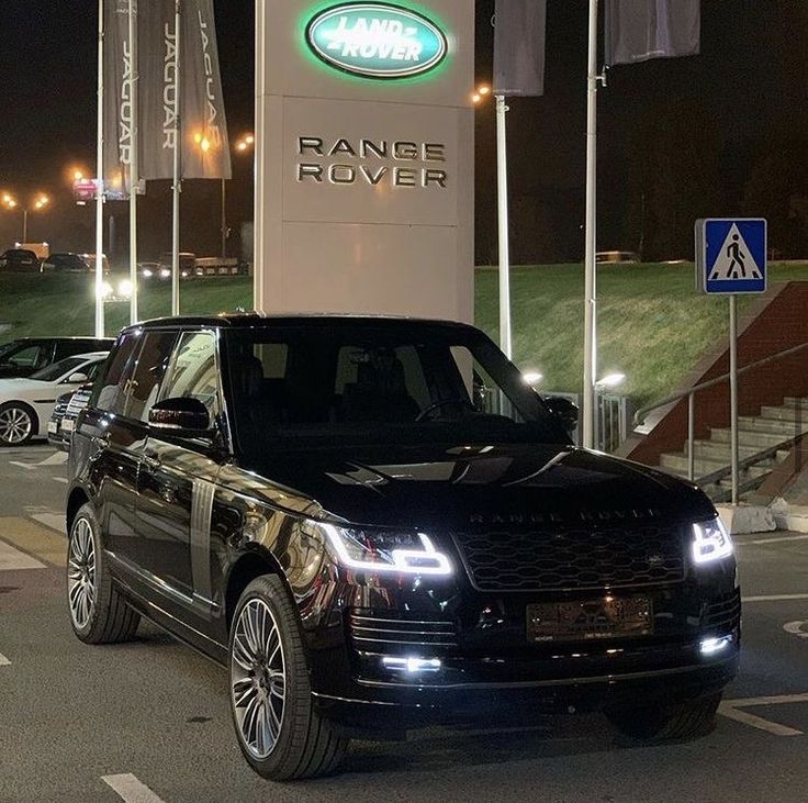 an suv is parked in front of a range rover dealership sign at night time