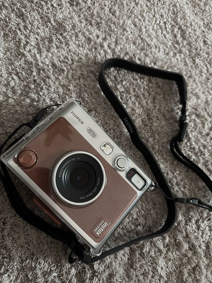 an old camera sitting on the floor with a strap around it's neck,