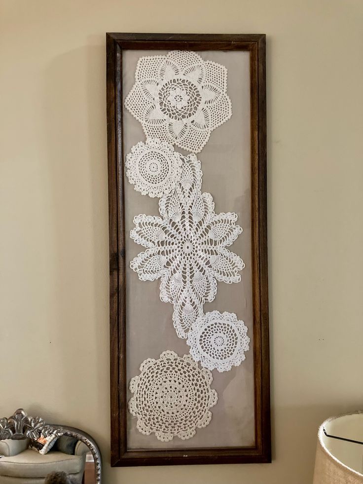 a white crocheted doily is hanging on the wall next to a mirror