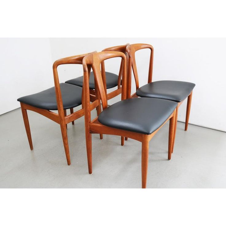 three wooden chairs with black leather seats are sitting in front of each other on a white floor