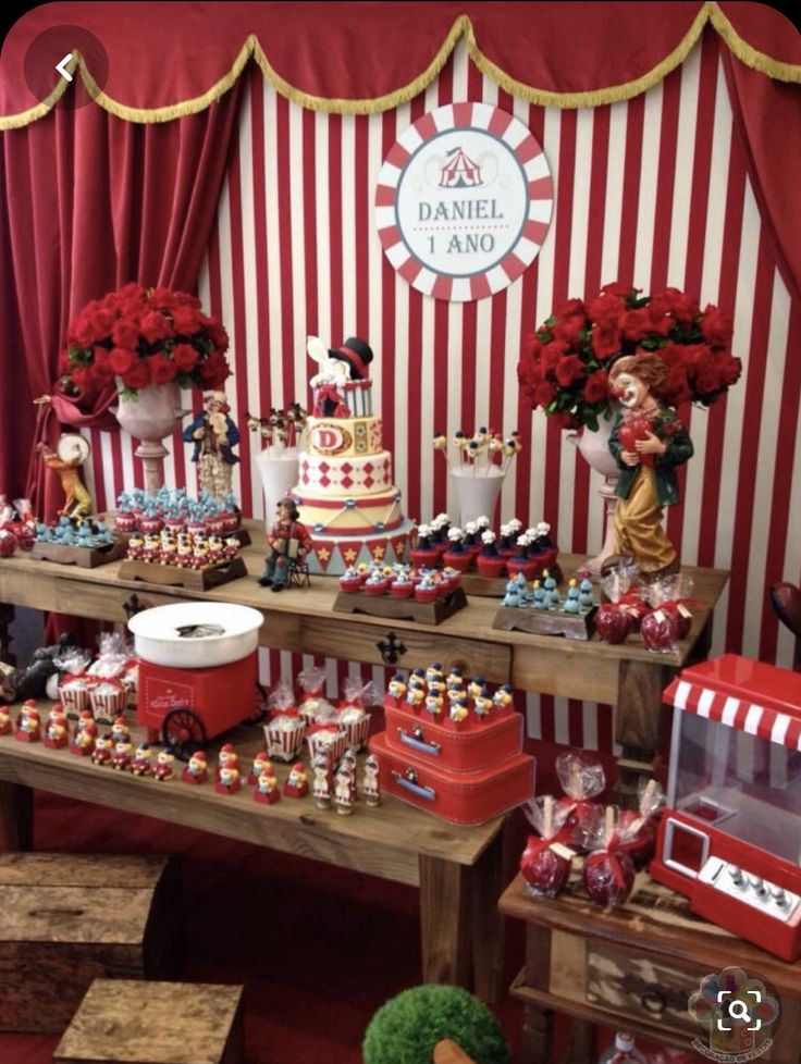 a table topped with lots of cakes and desserts next to a red striped wall