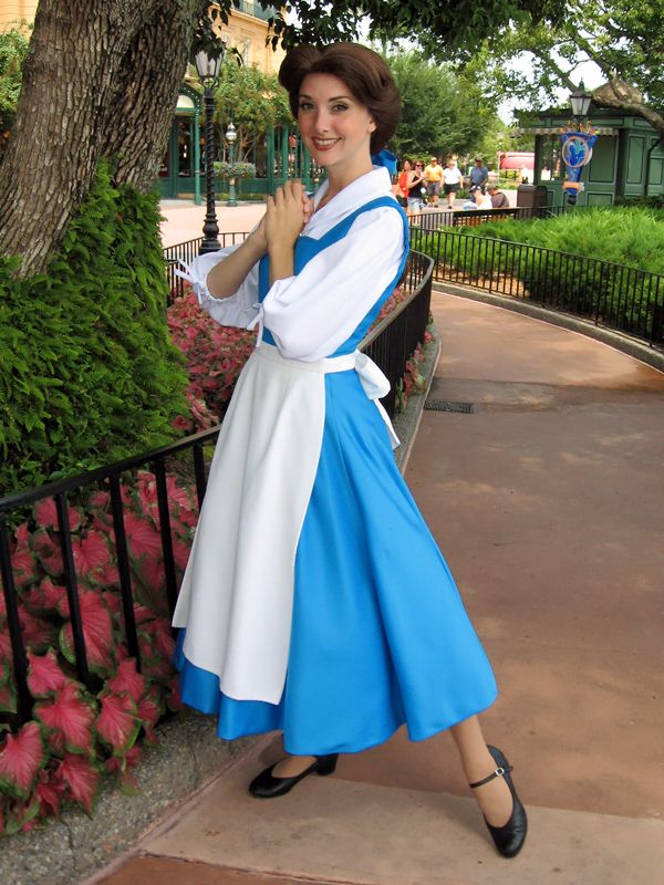 a woman in a blue and white dress standing next to a tree