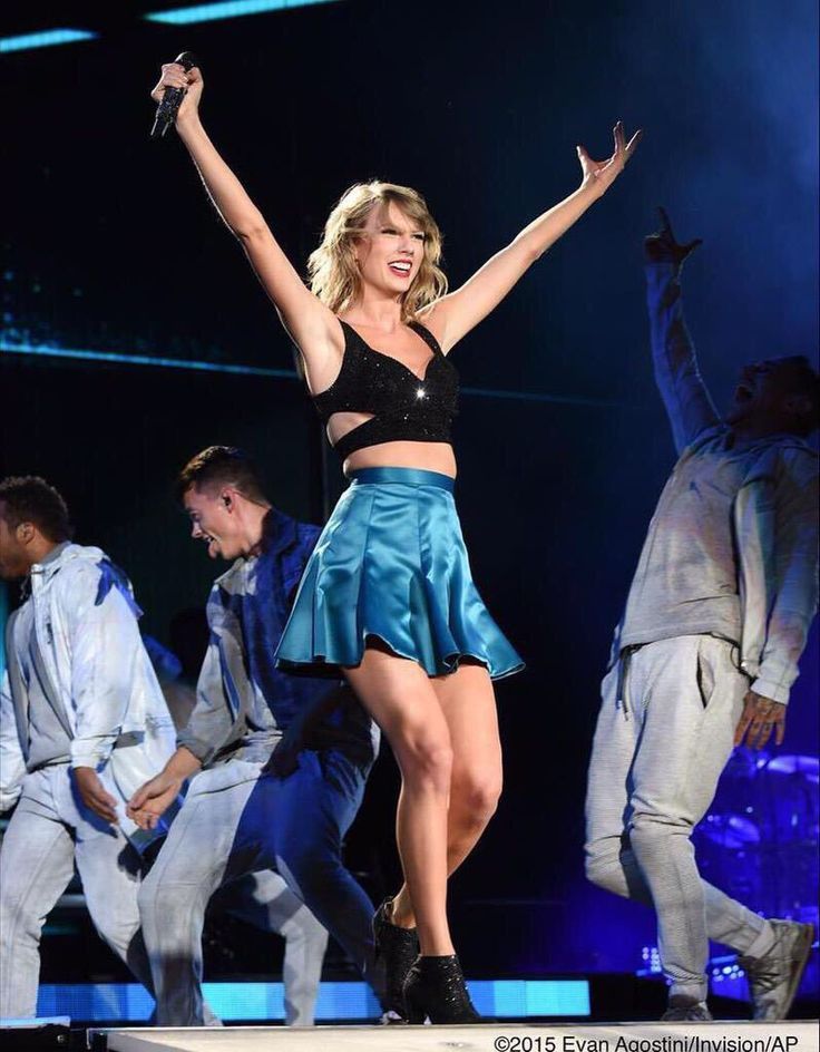 taylor swift performing on stage with her arms in the air