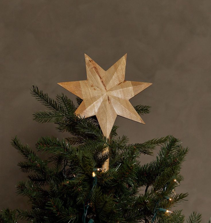 a wooden star decoration on top of a christmas tree