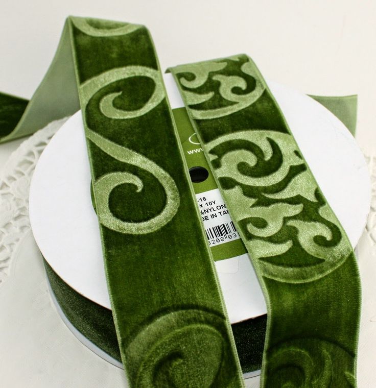 a close up of a plate with a green ribbon on top of it and another white plate in the background