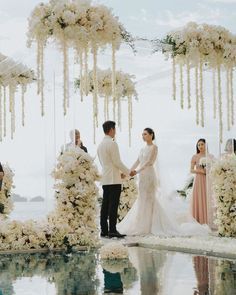 a couple getting married in front of an outdoor wedding ceremony with white flowers and greenery