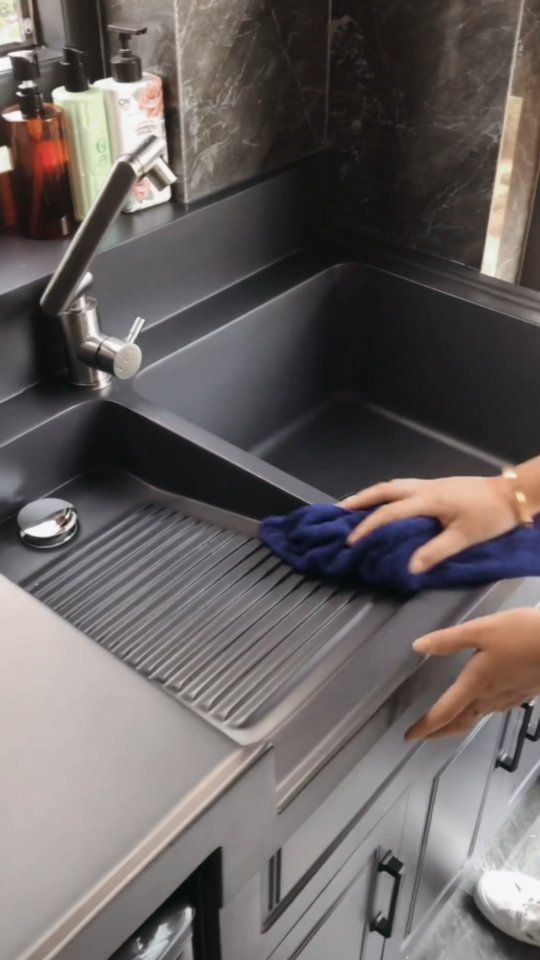 a doll is cleaning the kitchen sink with a blue towel and cloth on it's arm