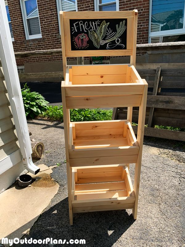 a wooden stand with a chalkboard on top and some plants growing out of it