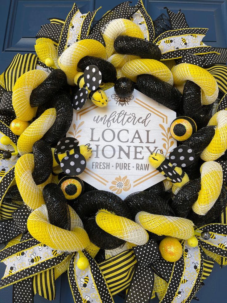 a yellow and black mesh wreath on the front door to a local honey fresh pure - raw store