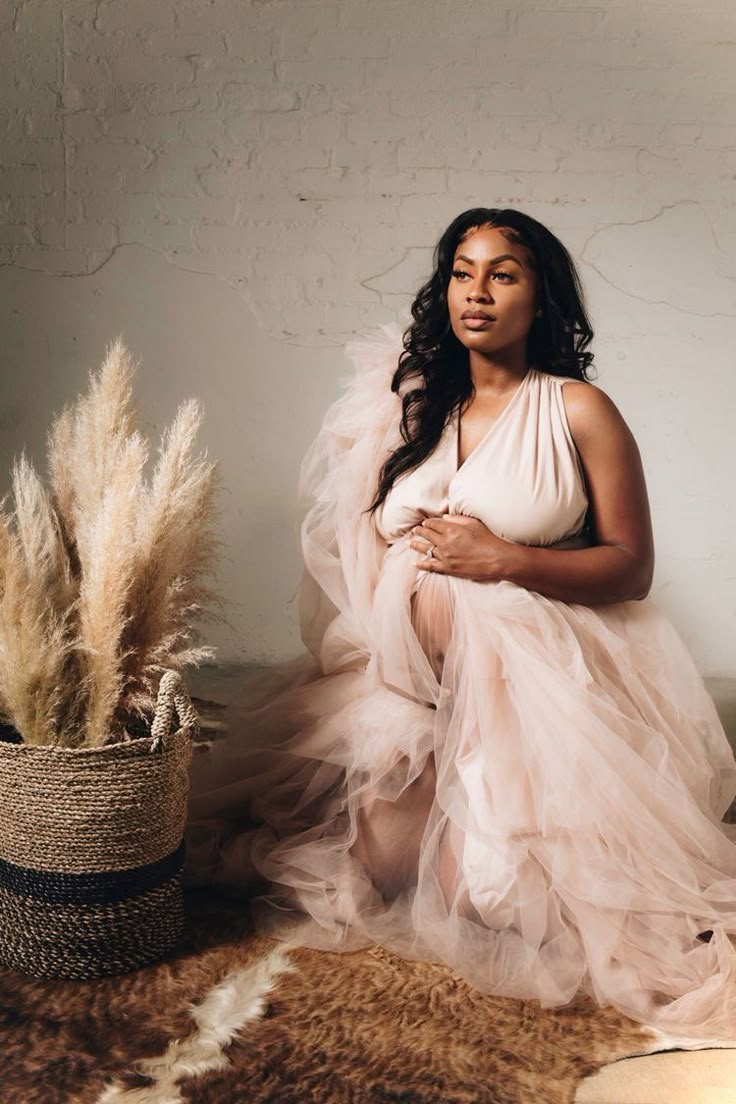 a woman in a dress sitting next to a potted plant on a fur rug