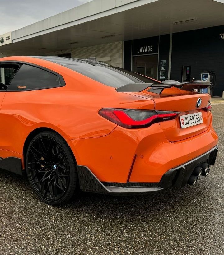 an orange sports car parked in front of a building