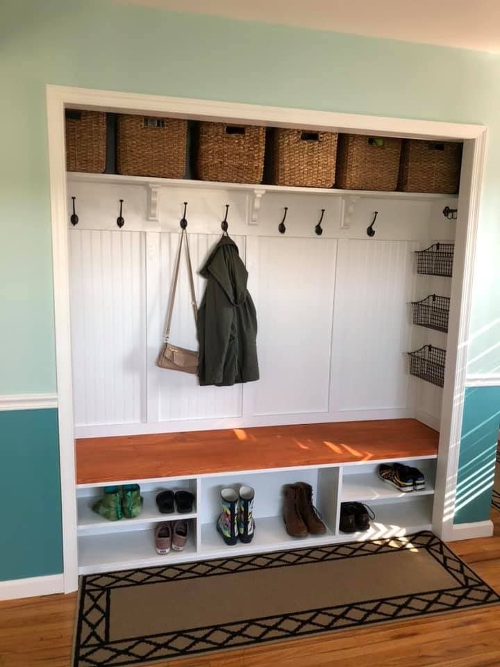 a coat rack with shoes and coats hanging on it's sides next to a rug