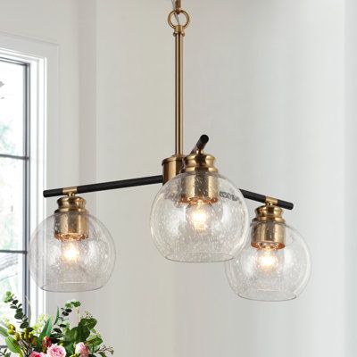 three lights hanging from a ceiling fixture in a room with white walls and flowers on the table