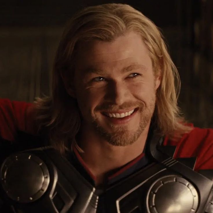 a man with long blonde hair wearing armor and smiling at the camera while posing for a photo