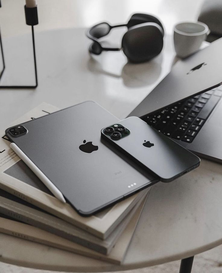 two laptops are sitting next to each other on a table with books and headphones