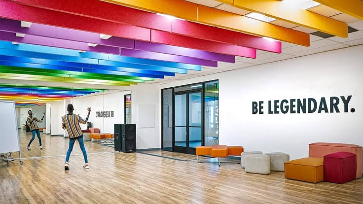 two people are dancing in an office with brightly colored beams on the ceiling above them