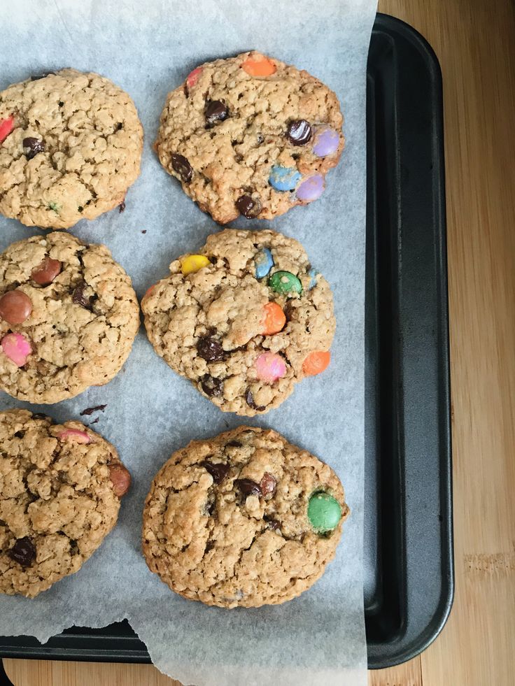 cookies with m & m's and candy are on a baking sheet, ready to be eaten