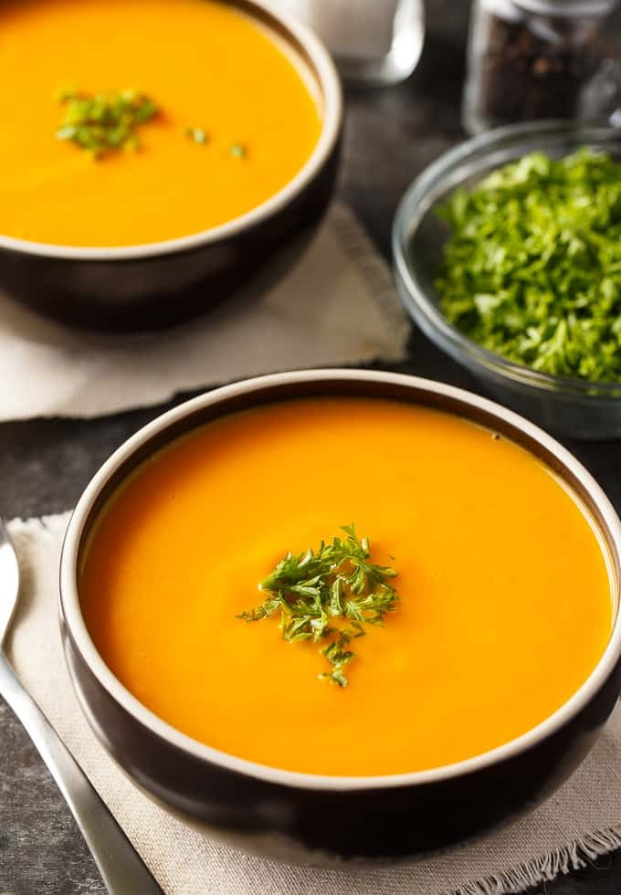 two bowls filled with soup and garnished with parsley