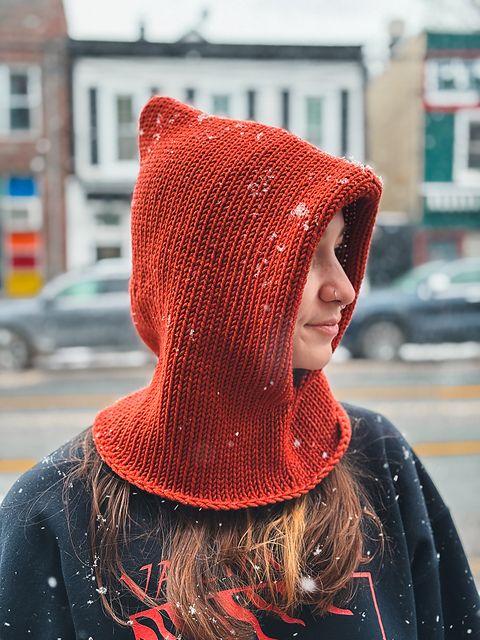 a woman wearing a red knitted hoodie in the snow