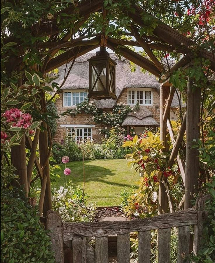 an open gate leading to a house with flowers in the front yard and garden behind it