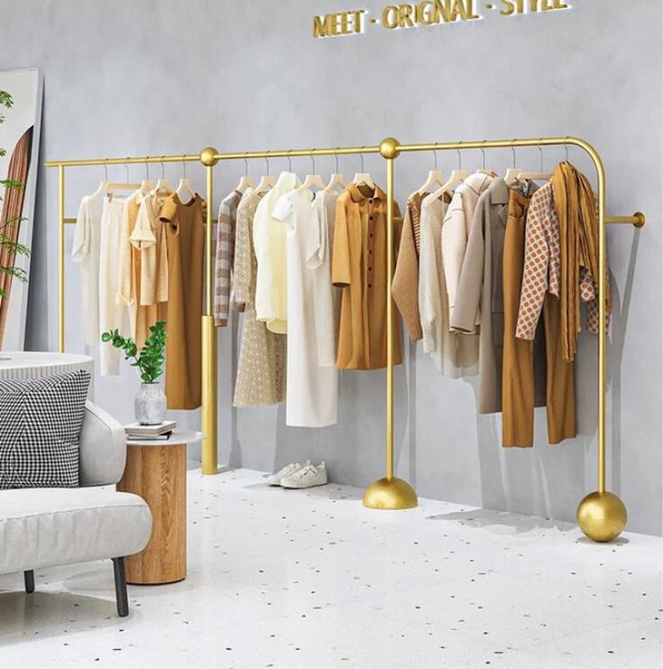 a room filled with lots of clothes hanging on metal racks next to a white couch