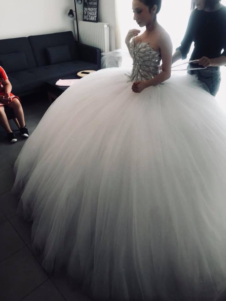 a woman in a white dress standing next to a couch