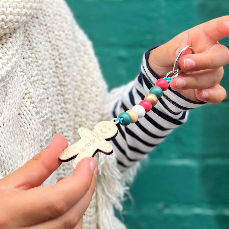 a person holding a small wooden cross keychain in their left hand and wearing a striped sweater