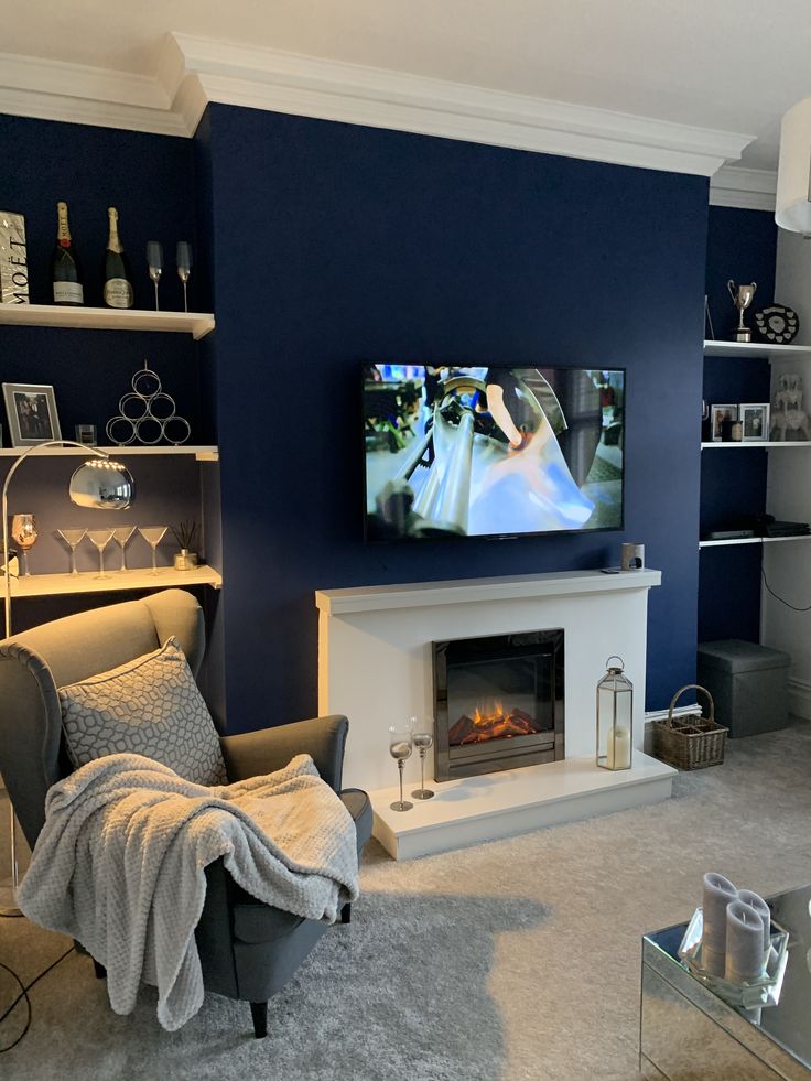 a living room with blue walls and a television mounted on the wall above a fireplace