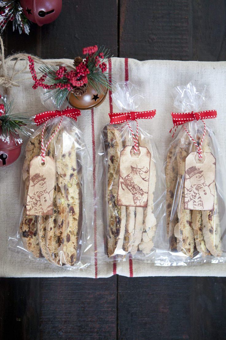 three cookies wrapped in cellophane and tied with red ribbon on top of a table