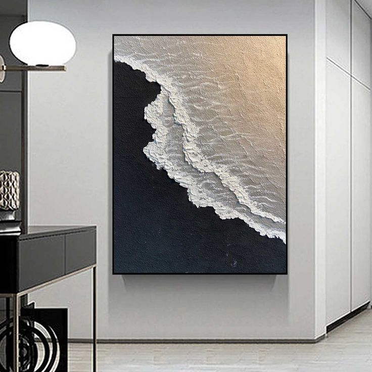 an abstract painting hangs on the wall next to a black and white desk in a modern office